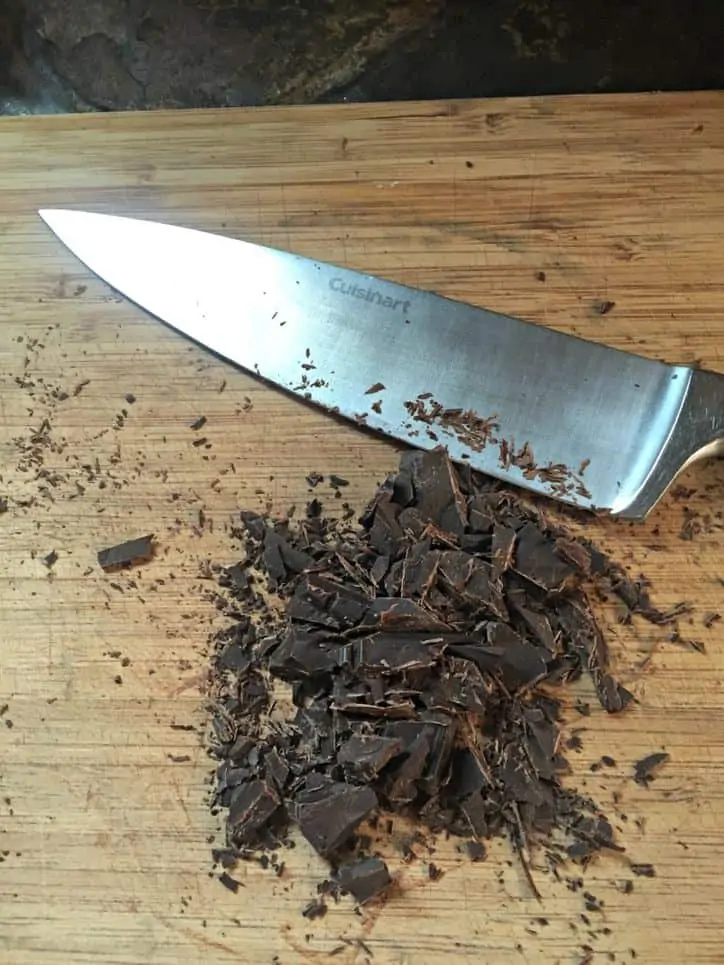Large knife on cutting board with chopped chocolate pieces