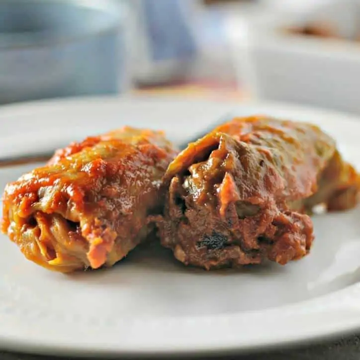 Two whole stuffed cabbage rolls on a white plate