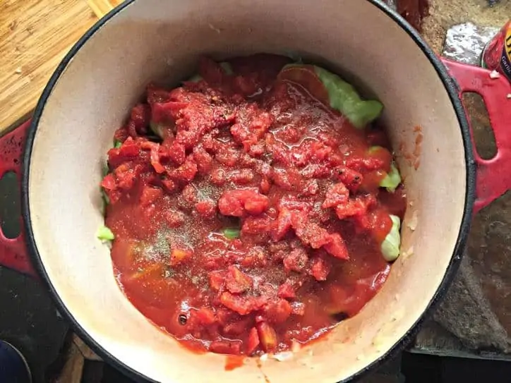 dutch oven with cabbage rolls covered with diced tomatoes