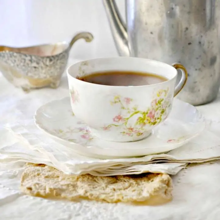 China Cup sitting on white cloth napkins with silver pitcher in the background