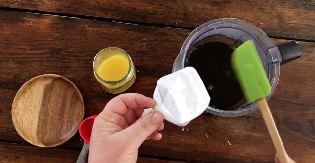 hand adding a sealed coffee filter to the hot tea with orange juice in background