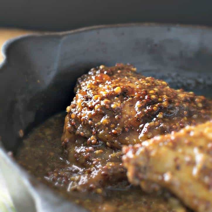 A cast iron skillet with a piece of chicken baking in it