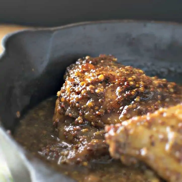 A cast iron skillet with a piece of chicken baking in it