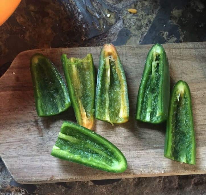 4 Jalapenos cut in half with seeds and ribs removed on a cutting board