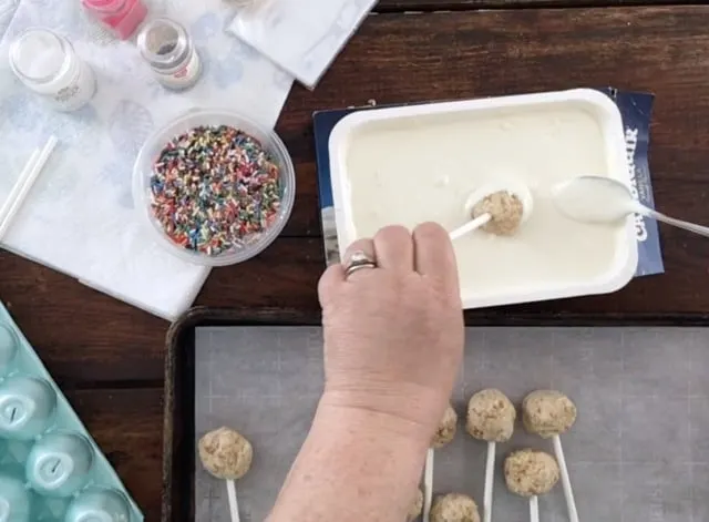 Dipping the Easter Cake Pops into the chocolate with sprinkles in background