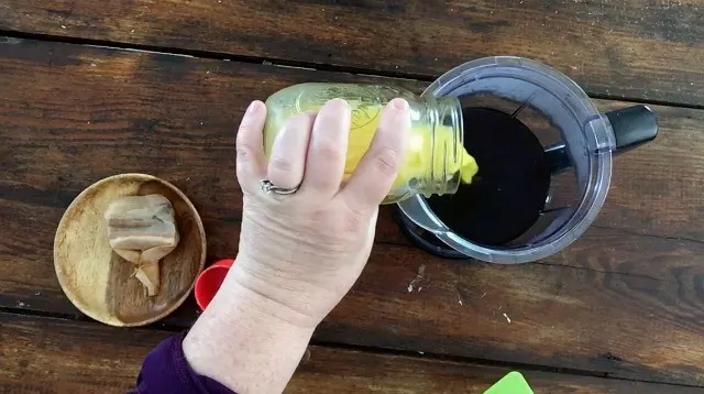 Adding orange juice to the russian tea with red measuring cup in the background