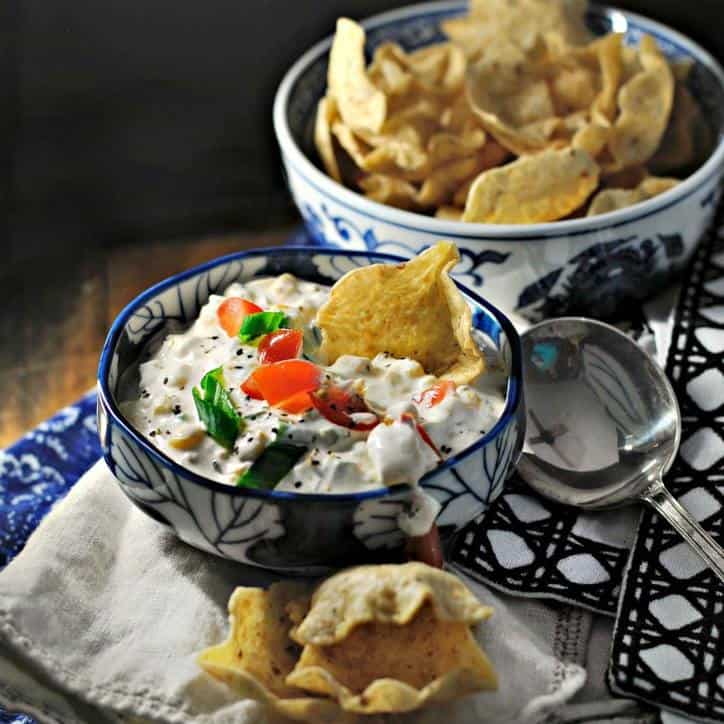 Blue bowl of corn dip with scooping chips, blue napkins
