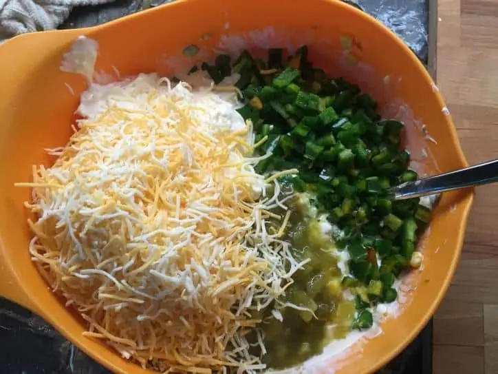 A large orange bowl with all of the ingredients and a spoon