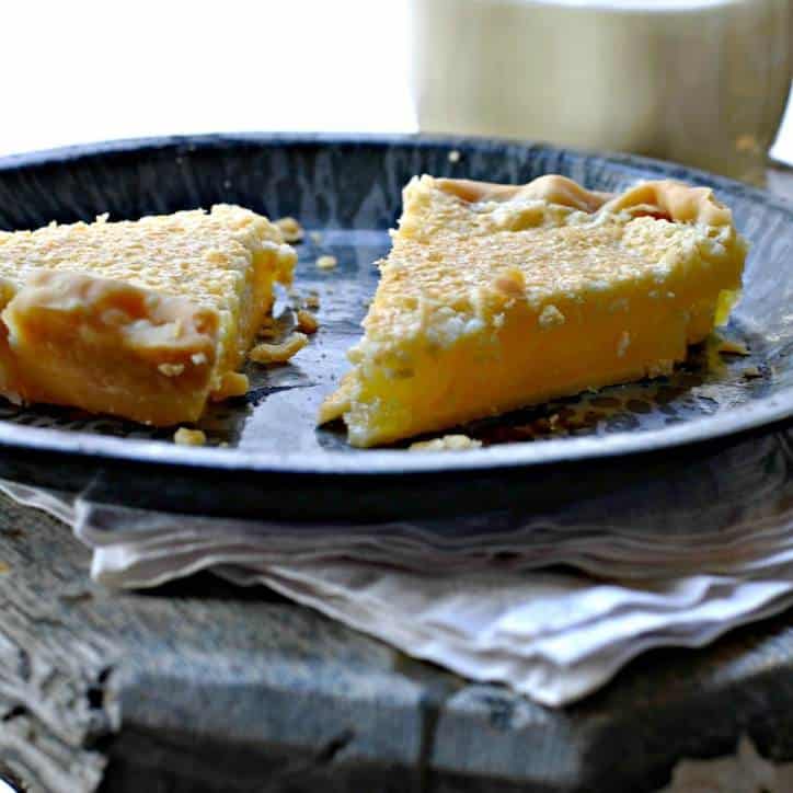 A photo of a slice of pie from the side sitting on a blue gray plate with white napikin underneath