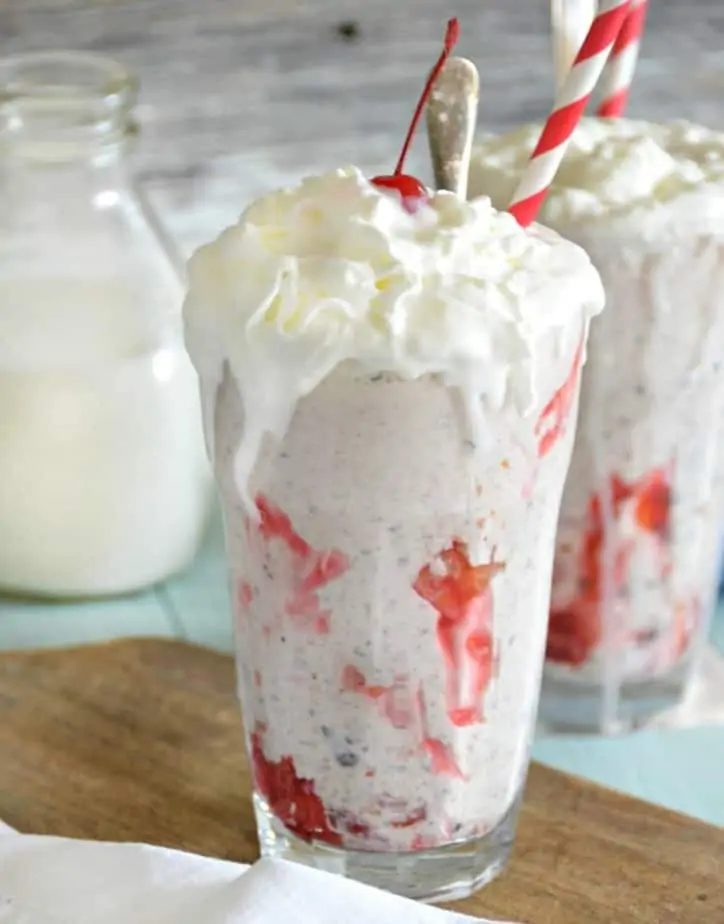milk shake with melting whipped cream and bottle of milk in background