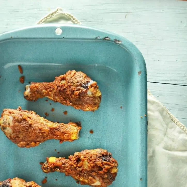 baked chicken legs in a blue pan with towel