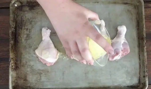 hand pouring butter over chicken legs