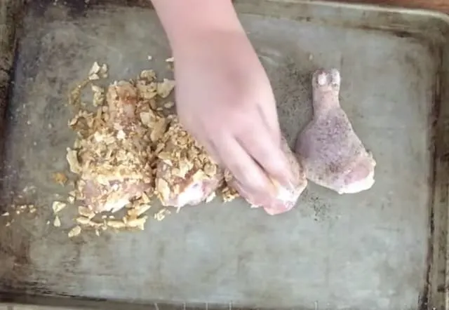 hand adding crushed mix to chicken legs