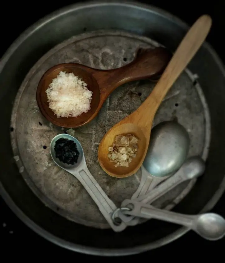 an aluminum pan with various measuring spoons full of spices