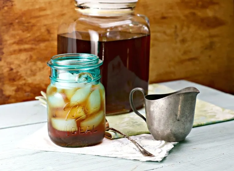 Southern Iced Tea in a glass pitcher, ball jar of tea, spoon and simple syrup server in foreground