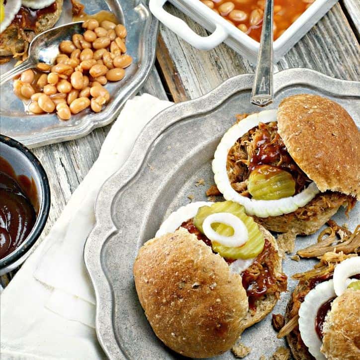 silver plate with barbecue sandwhiches with baked beans in the background on a wooden board