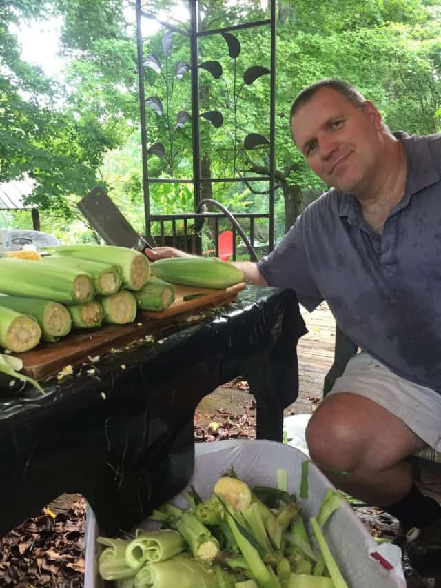 man sitting with corn shucks