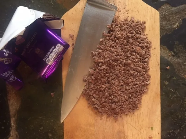 milk chocolate bar chopped super small on a cutting board