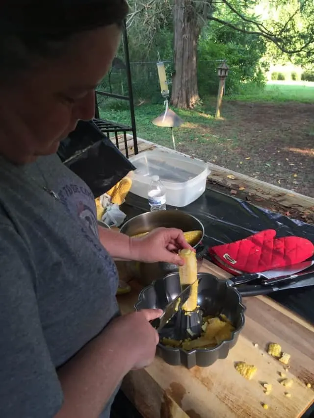 wendi cutting the kernels from the corn into a bundt pan