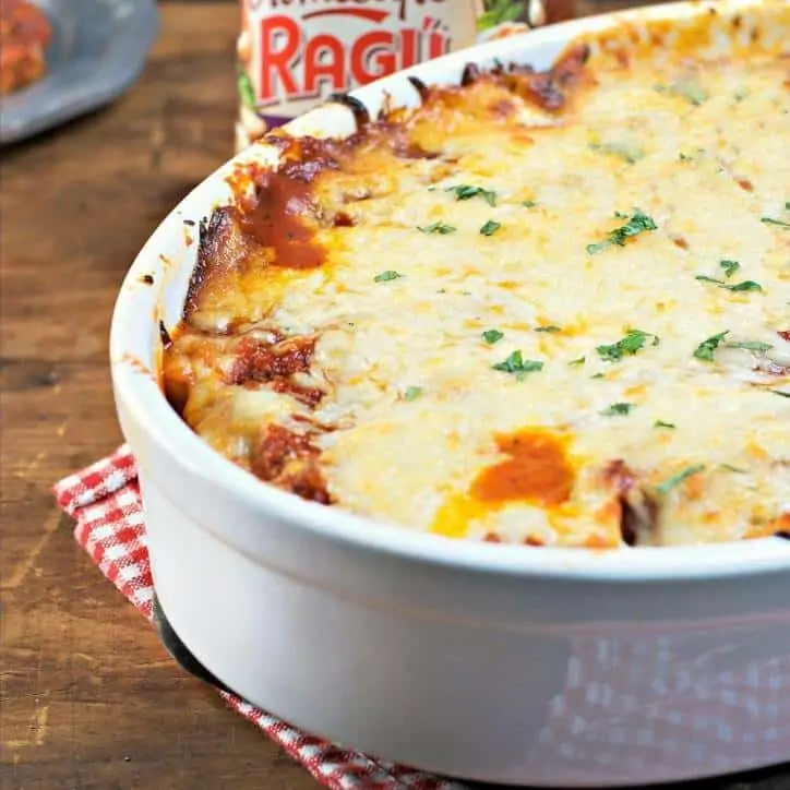 white baking dish of spinach stuffed shells with melty cheese on top sitting on a checked napkin