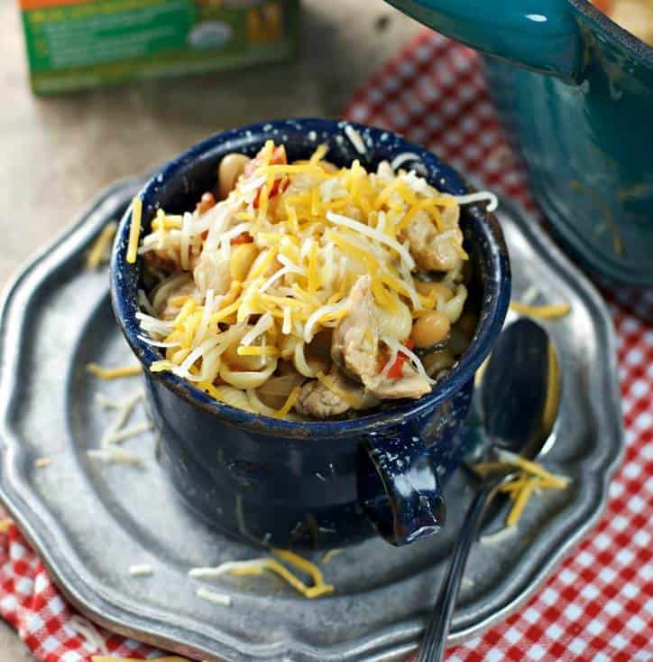 Blue enamel cup full of chili sitting on a silver plate with checked napkin in background