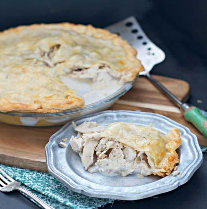 slice of chicken pie on a plate with whole pie in the background