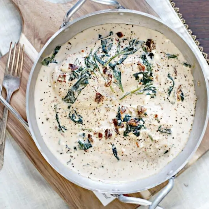 Silver pan of this tuscan chicken recipe on cutting board with fork.