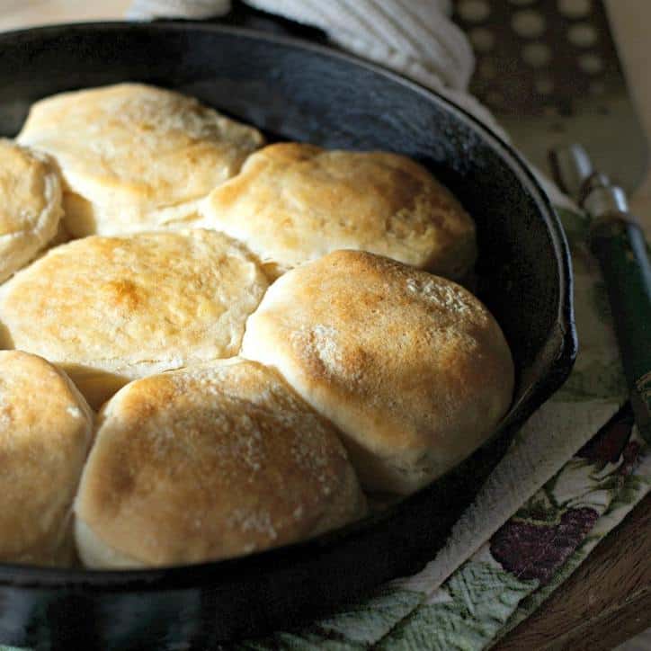 Canned biscuits in a cast iron skillet with light shining on them