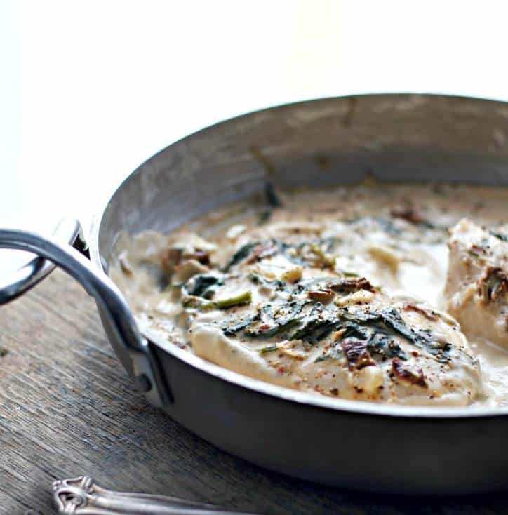 silver pan on a wooden background filled with spinach covered meat
