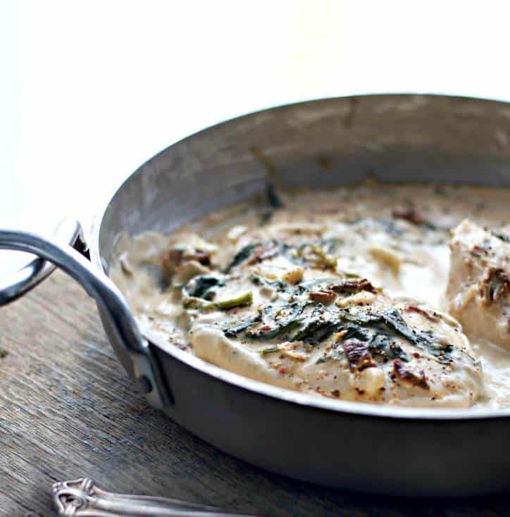 silver pan with Tuscan Chicken. Wooden table and fork handle in background.