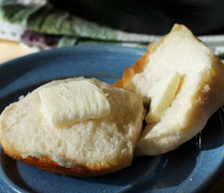 An open biscuits with melty butter showing the fluffy inside of the biscuit