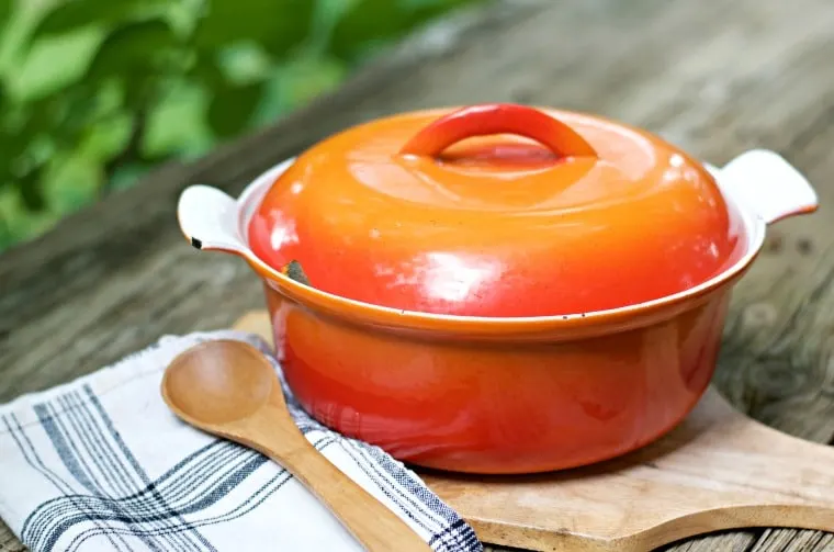 A photo of a heavy cast iron orange colored pot for cooking beans