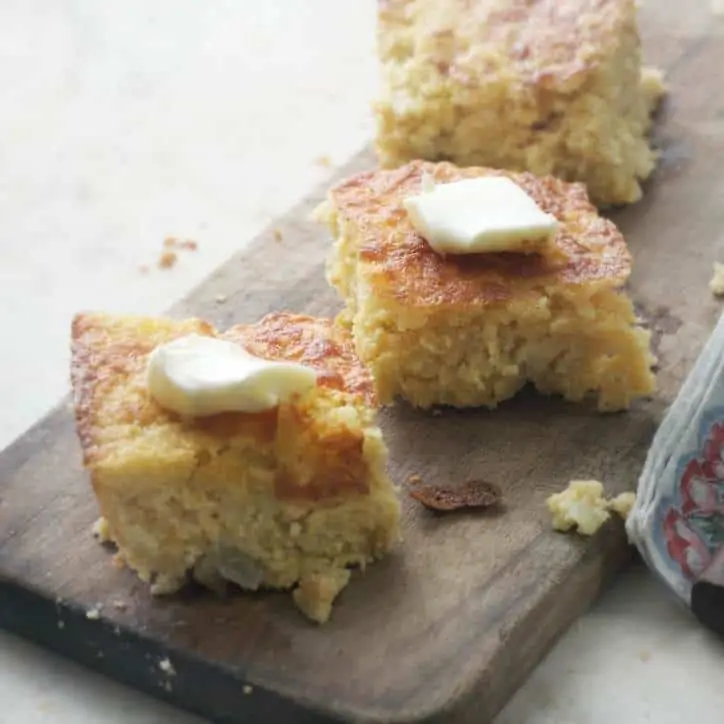 Southern Mexican Cornbread with butter on top and sitting on a cutting board - view from the side