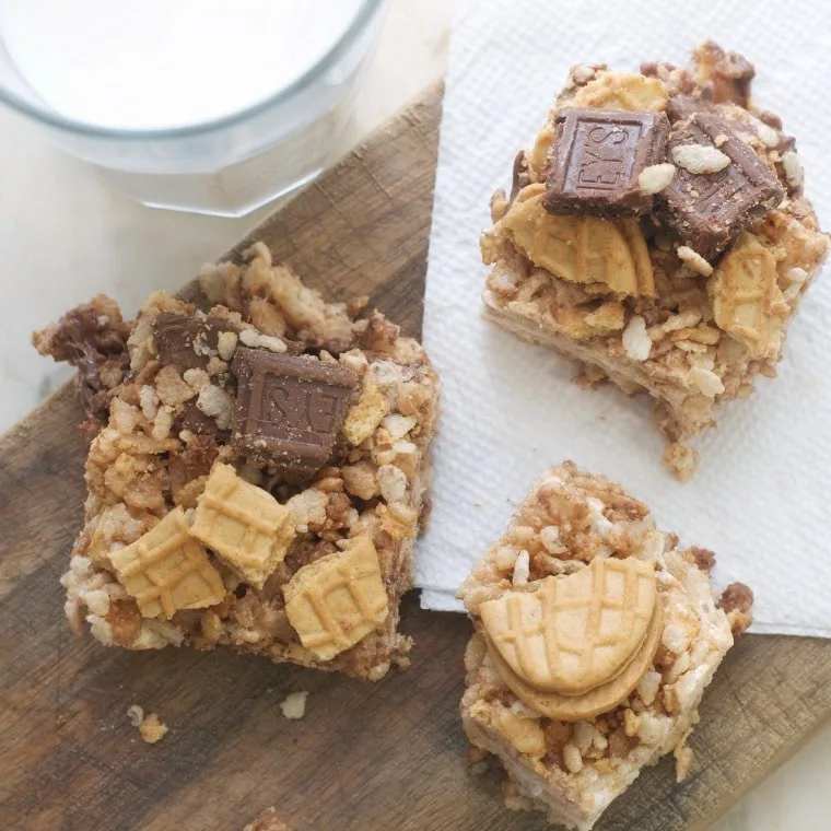 Chocolate Nutter Butter Crispy Treats sitting on a cutting board with a glass of milk
