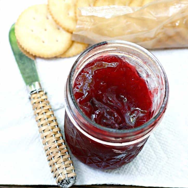 A photo from above of an open jar of CARDAMOM PLUM JAM with a pack of crackers