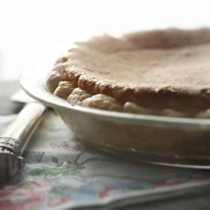 a whole pie from the side with morning light in the background flowered napkin and pie server