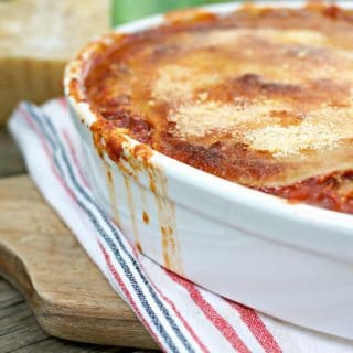 This is a photo of the Fried Green Tomato Parmigiana up close and with sauce running down the side of the pan