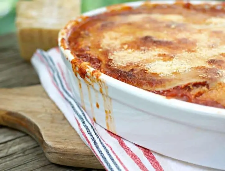 This is a photo of the Fried Green Tomato Parmigiana up close and with sauce running down the side of the pan