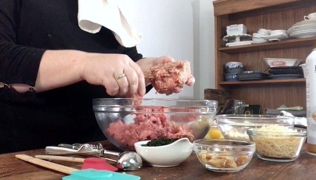 Wendi tearing up meat and placing into a glass bowl with small dishes of other ingredients in foreground