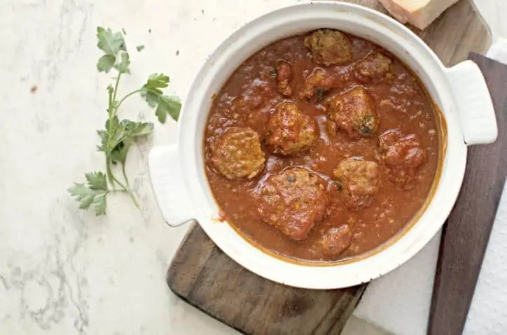 A view from above of the meatballs without breadcrumbs in the pot they are cooked in with some parsley