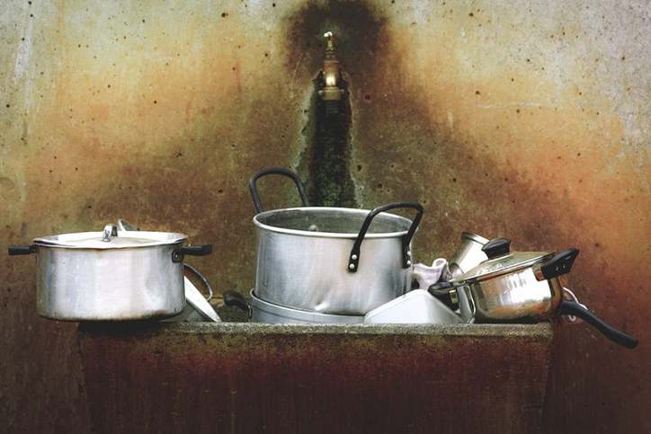 Pots and pans piled up in an outdoor kitchen for how to keep your kitchen organized