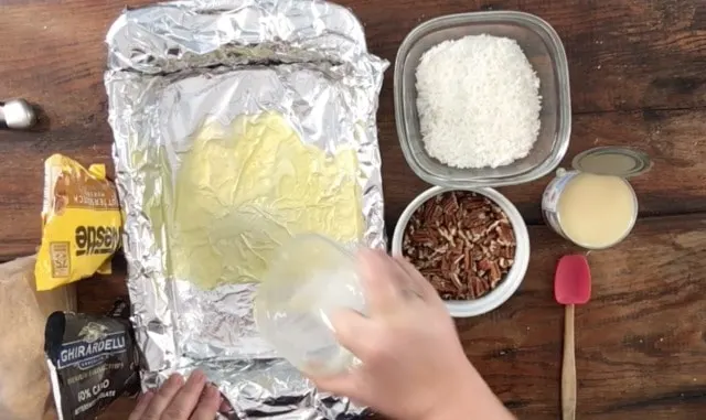 Butter being poured into a 9x13 pan covered in foil 