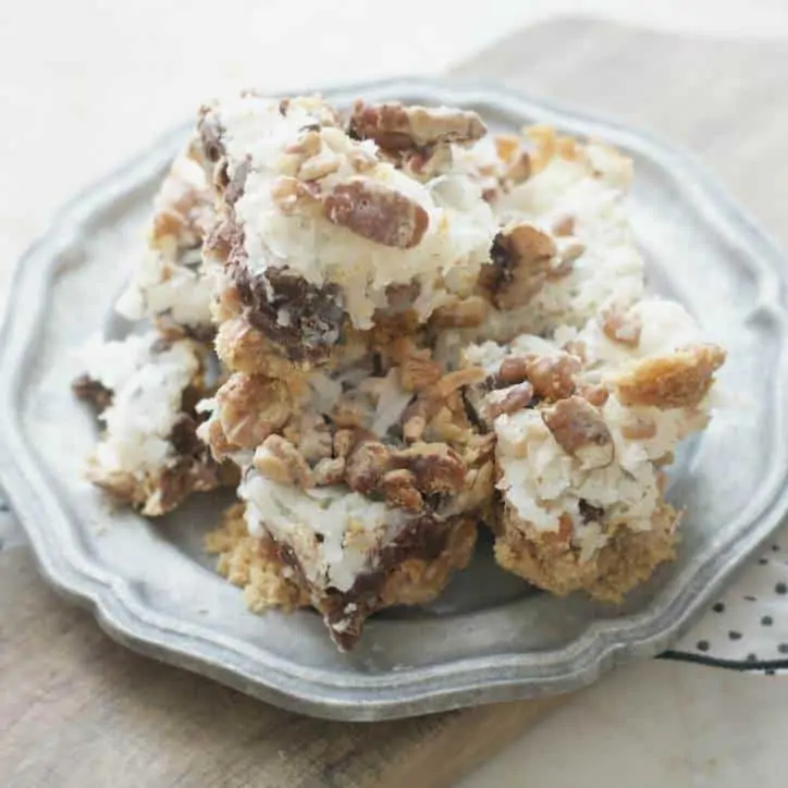 A silver plate full of old fashioned seven layer bars showcasing the rich pecans and fluffy coconut