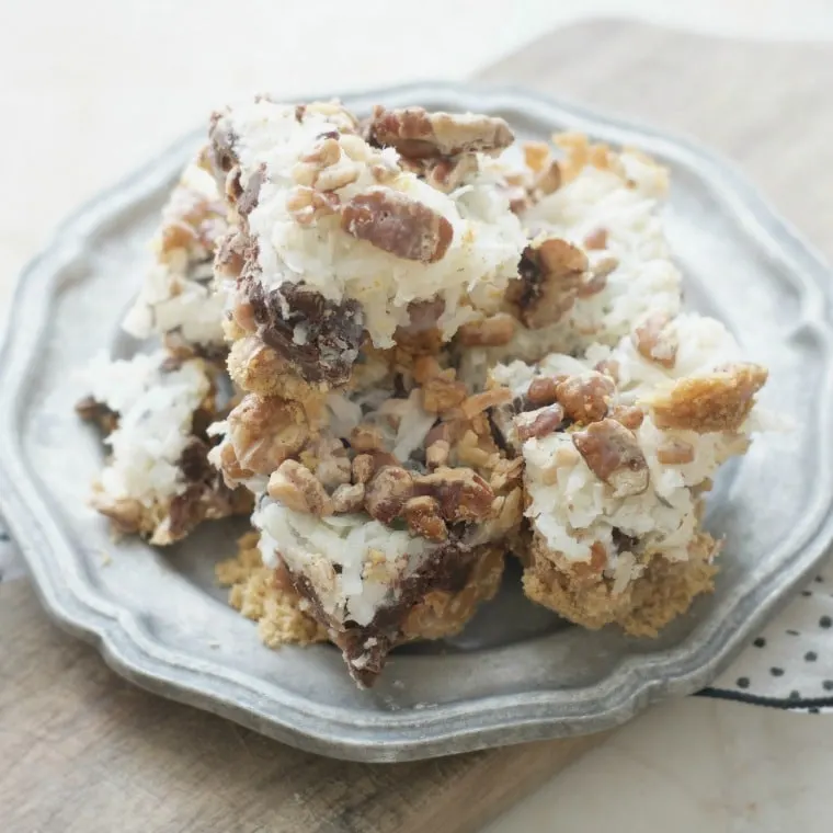 A silver plate full of old fashioned seven layer bars showcasing the rich pecans and fluffy coconut