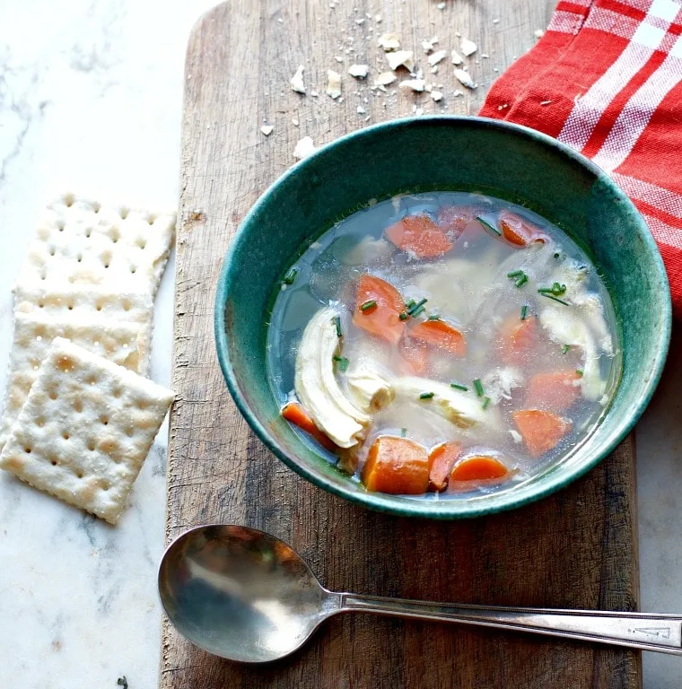 green bowl of soup with crackers and spoon