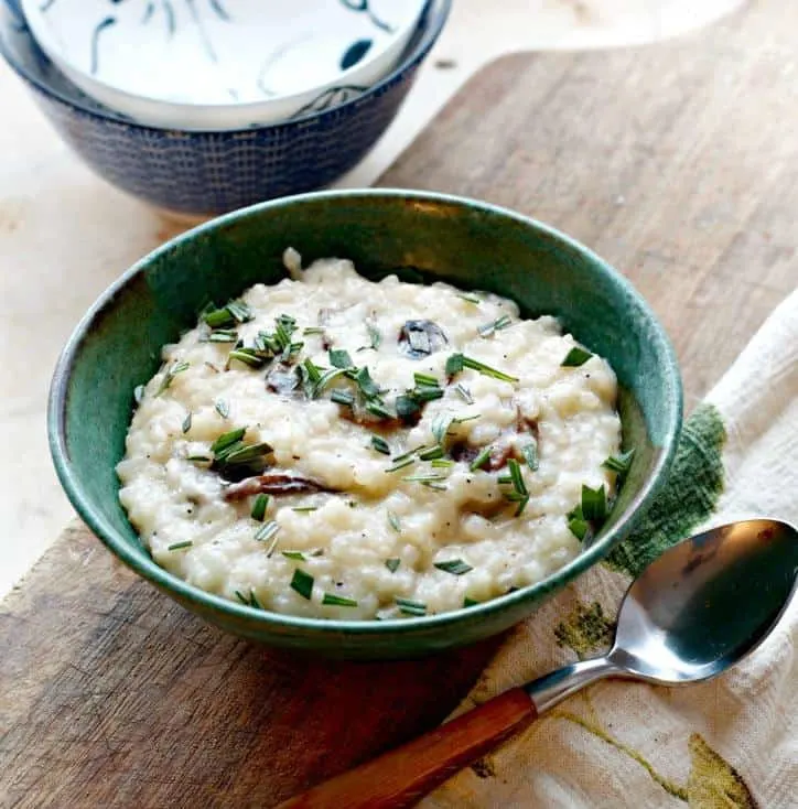 A photo of Creamy No Stir Parmesan Mushroom Risotto at a medium distance with a spoon and two bowls