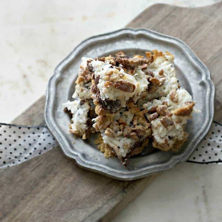 A view from far above of OLD FASHIONED SEVEN LAYER BARS on a sliver plate with a polka dot ribbon beneath the plate