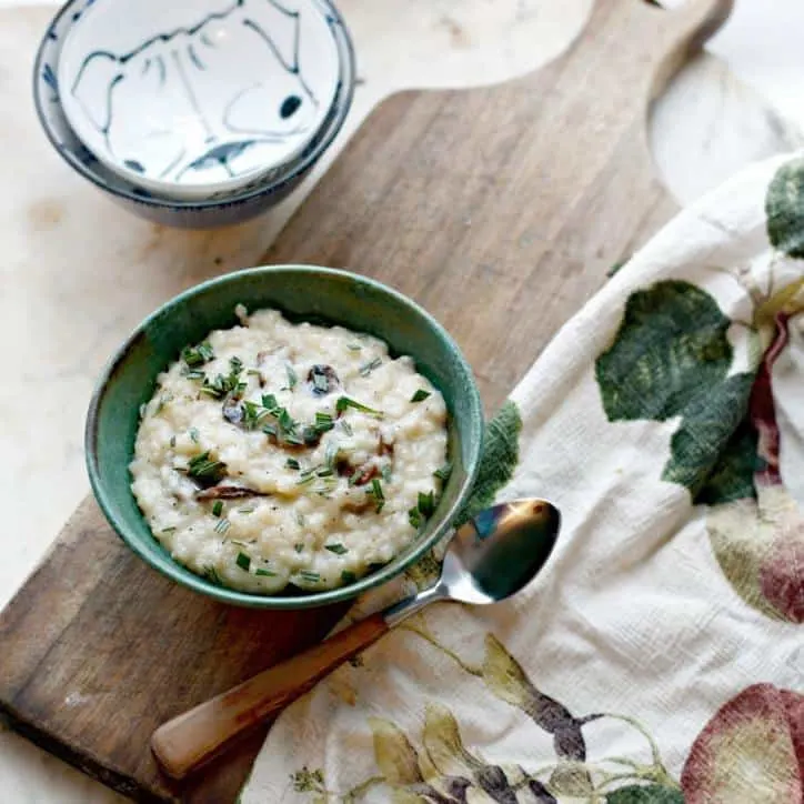a photo of Creamy No Stir Parmesan Mushroom Risotto overhead and at a distance with a towel and spoon and bowls in the frame
