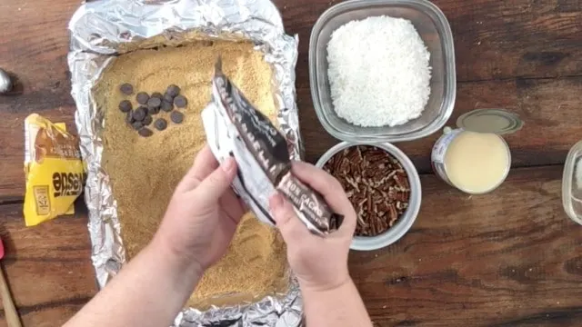 Chocolate Chips being poured over the top of the graham cracker crust 