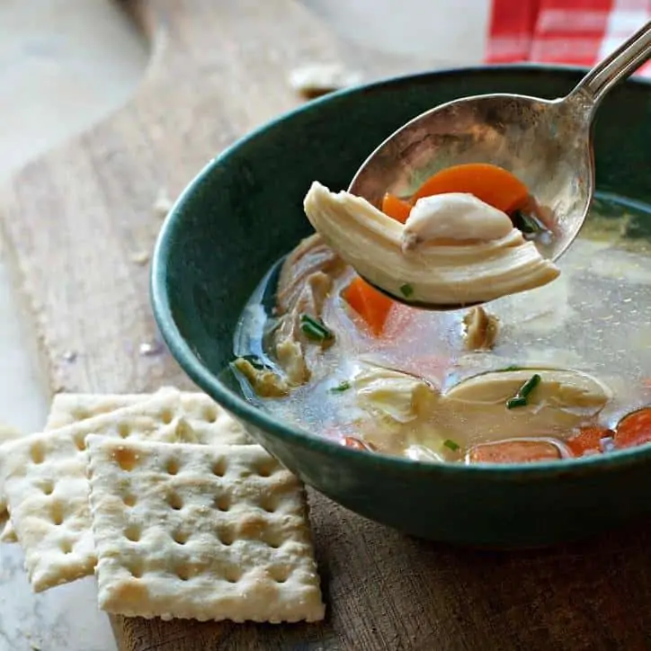 A photo of a spoonful of chicken meat in chicken soup